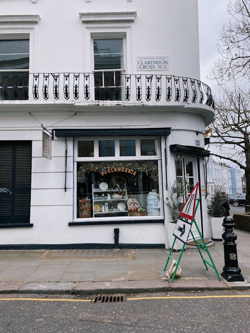 The ground-floor window of a white building housing a boulangerie displays a clean, well-maintained interior with neatly arranged plates, bowls, and baking-related items visible through the glass. Out